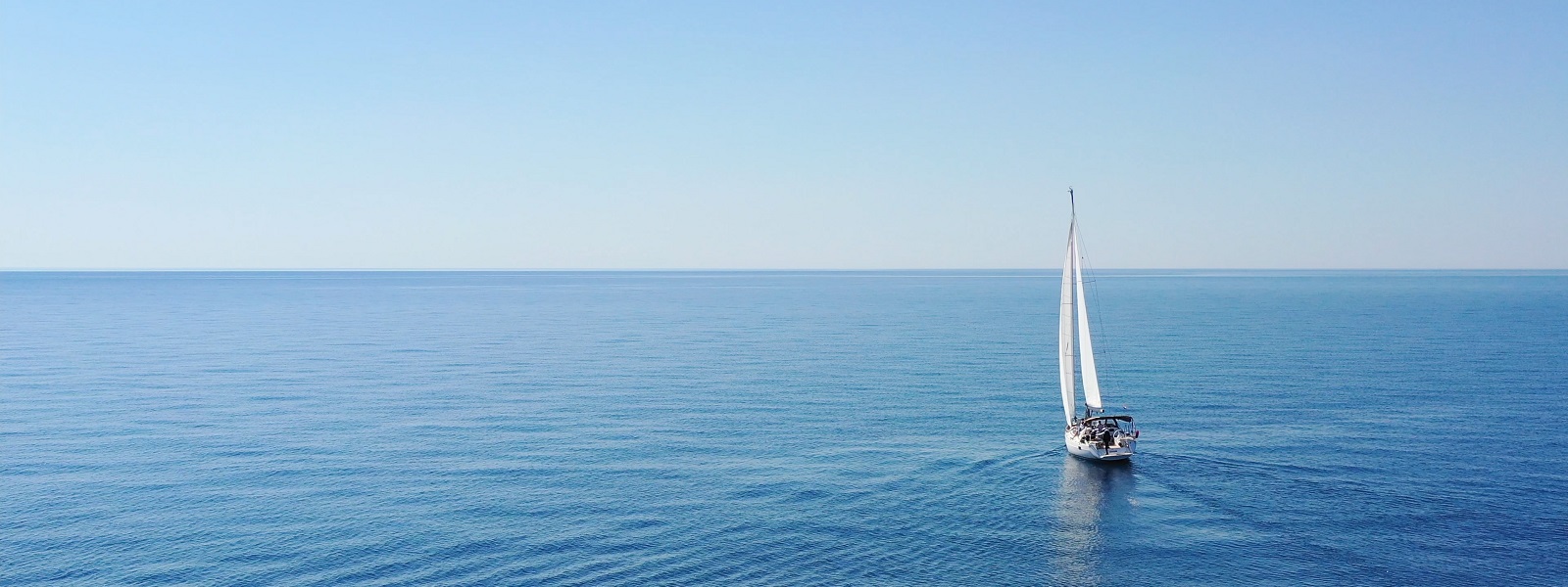 A yacht alone in a blue sea under a blue sky