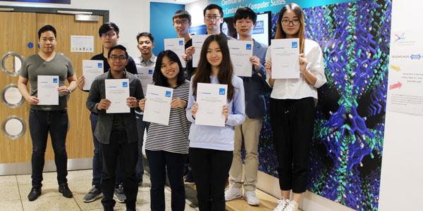 Summer school 2017 students standing in the James Weir corridor holding their certificates and smiling at the camera