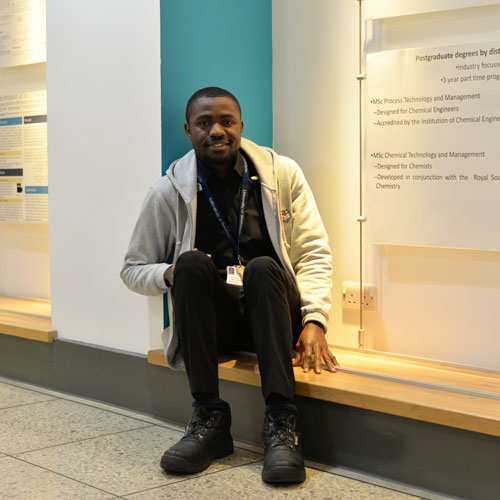 Chemical engineering PhD student Precious sitting in the James Weir corridor smiling at the camera
