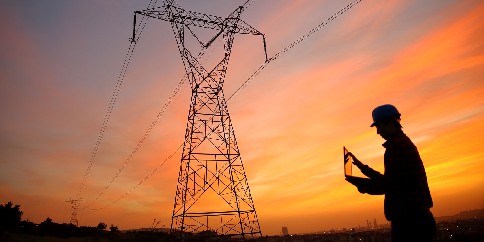 Electrical engineer stands under a pylon while working on an ipad