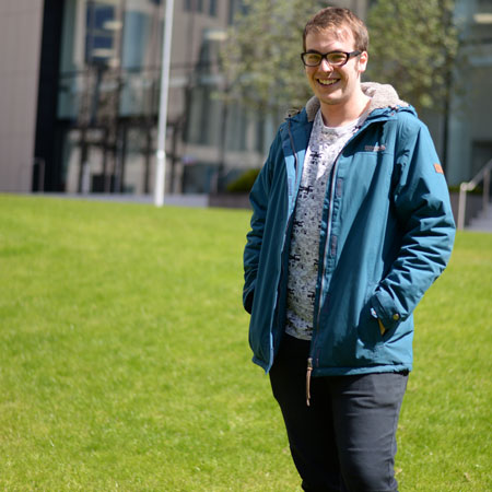 Politics student Fraser standing on the grass in front of the Technology & Innovation Centre