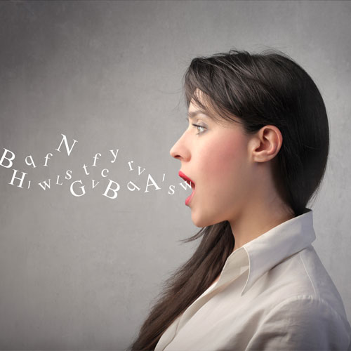 a side profile of a woman who stands with her mouth open as words fly out 