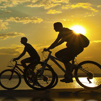 Two people cycling in the sunset