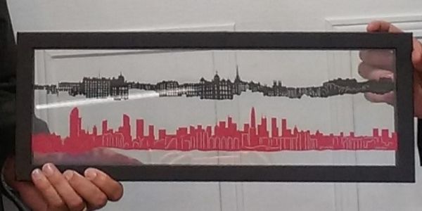 A cut glass depiction of Edinburgh and Shenzhen's skylines in a black presentation frame.