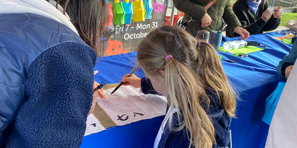 Child writes numbers in Chinese with ink brush at calligraphy stand Child writes numbers in Chinese with ink brush at calligraphy stand