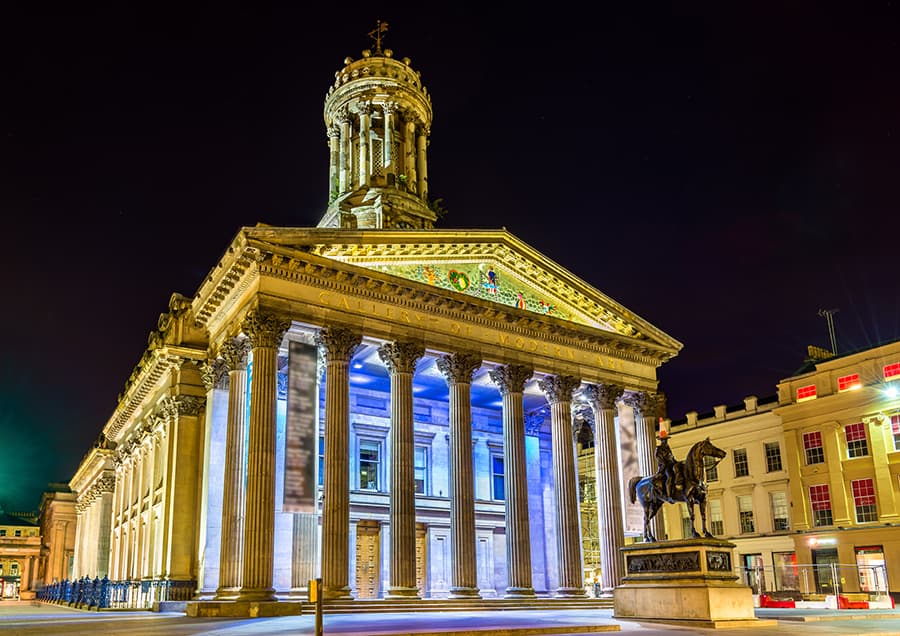 Gallery of Modern Art lit up at night, with the Duke of Wellington statue standing in front