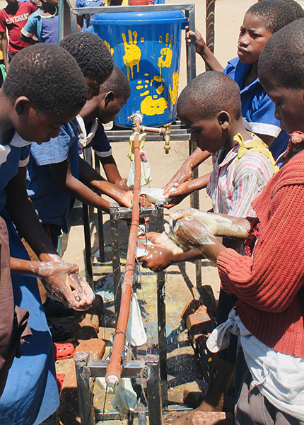 Young African children wash their hands at an outdoor washing station