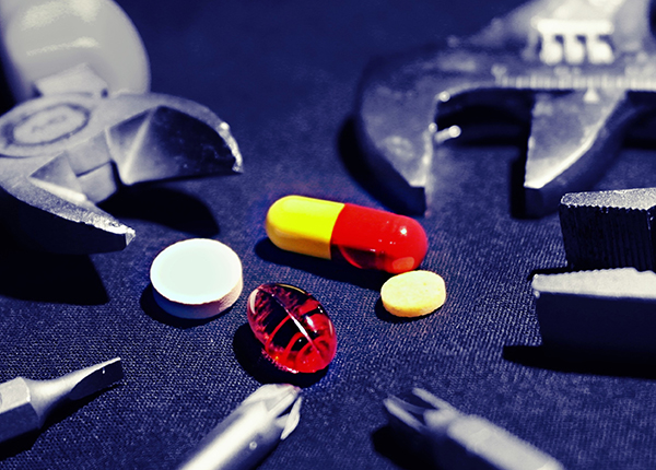 An assortment of colourful pills lie surrounded by tools