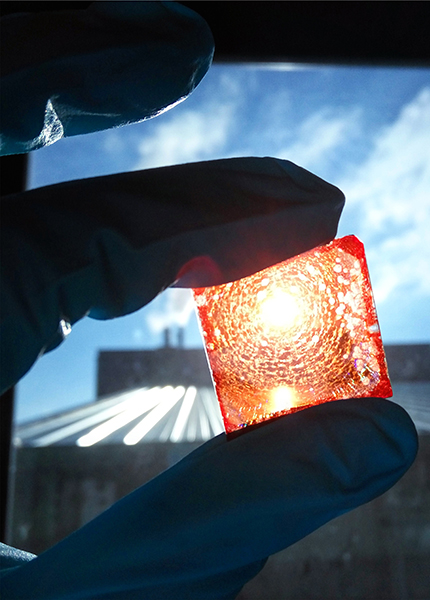 A close up of a hand holding a small orange square – a lead free alternative material for solar panels