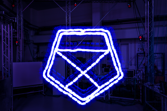 A darkened lab with the University logo painted in light using a drone