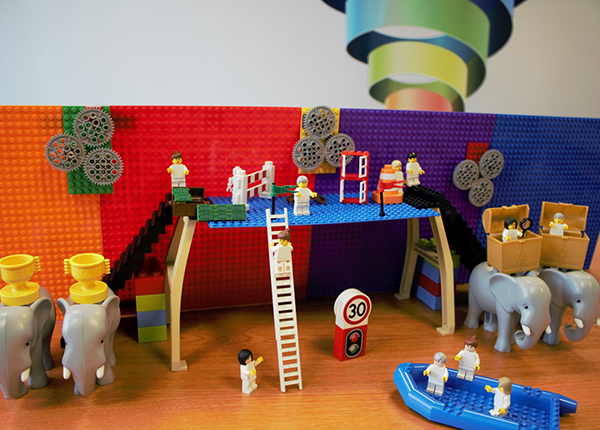 A scene created using Lego shows people arriving at a platform, in a boat. People wait on the platform ready to help them