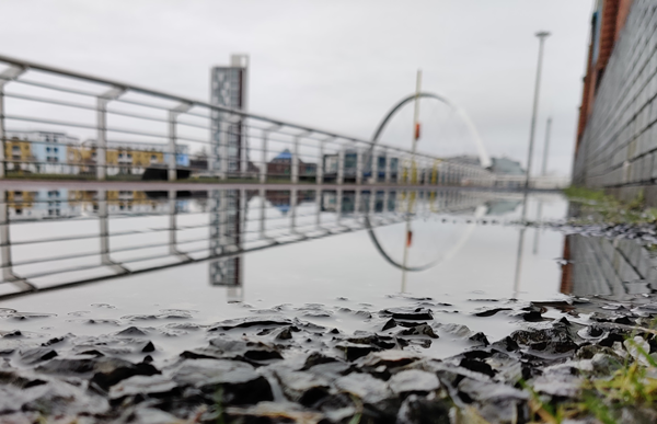 A flooded walkway next to a river in a city