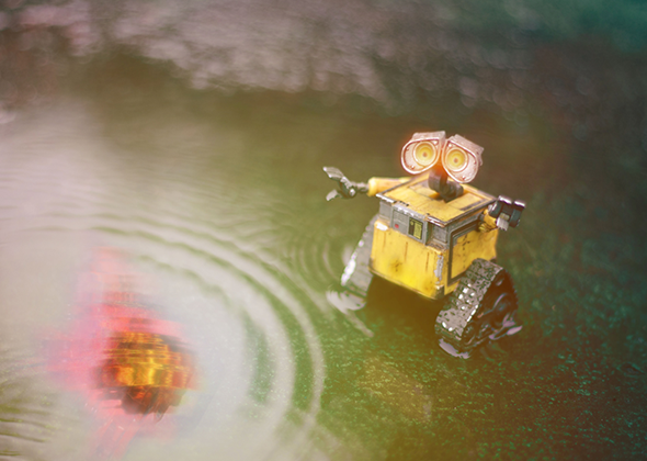 A robot looking at the reflection of a meteor in a puddle