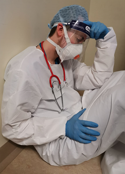 An exhausted medic in PPE kit sitting on the floor