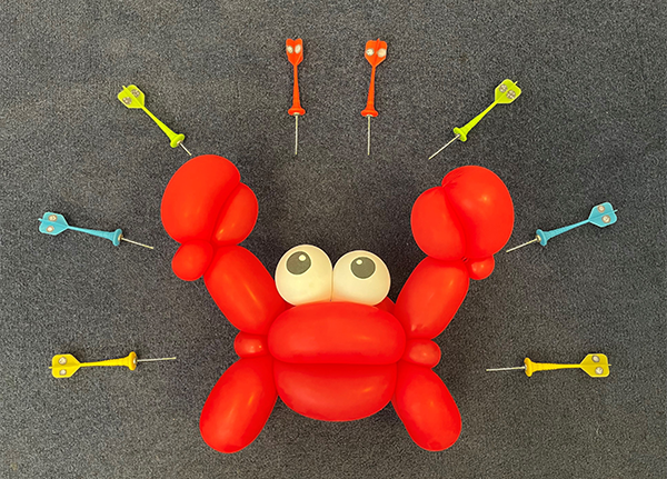 A red balloon crab, surrounded by darts with pictures of vesicles on them pointing at the crab