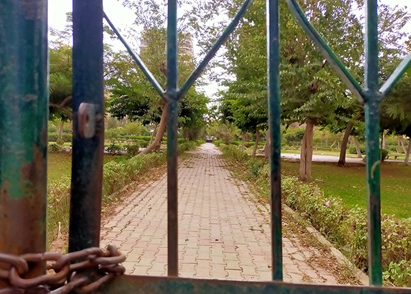Looking through a chained gate at a neglected city park