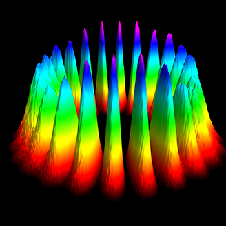 A 3D graphic representation of orbital angular momentum showing a circle of peaks going from red at the base through the spectrum of light, to magenta at the top