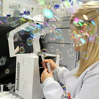 A researcher removes sample vials from a piece of lab equipment as bubbles float in the air