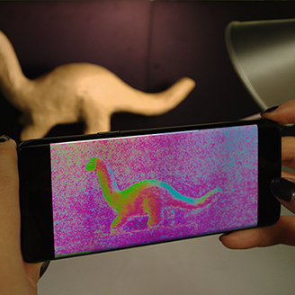 A mobile phone being used to image a dinosaur model with 3D imaging technology 