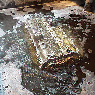 A car engine sits in an industrial bath as part of the remanufacturing process