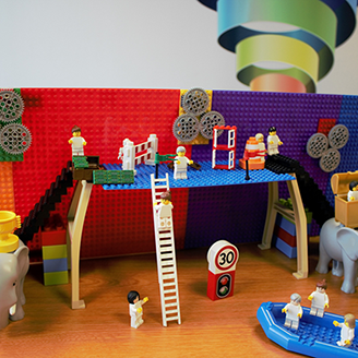 A scene created using Lego shows people arriving at a platform, in a boat. People wait on the platform ready to help them