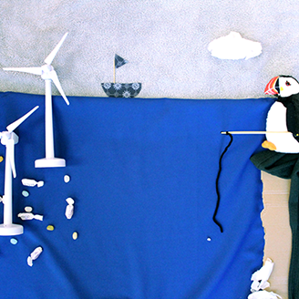 A collage representing a puffin on a cliff edge with a fishing rod looking over to fish swimming beneath offshore wind turbines