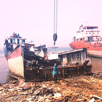 An old ship being dismantled on the shore surrounded by debris