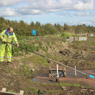 A man in high-viz clothing raking a former canal site