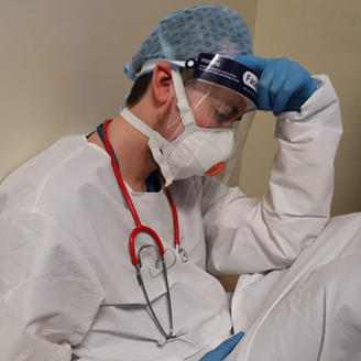 An exhausted medic in PPE kit sitting on the floor