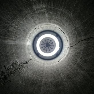 A black and white photo looking into a tunnel with an inspection camera at the end of it