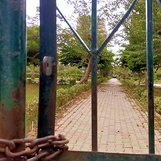 Looking through a chained gate at a neglected city park