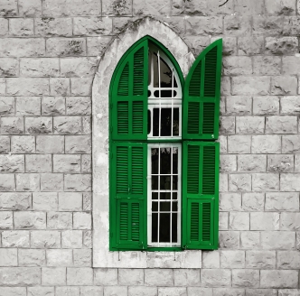 A close-up of a window with green shutters, one open