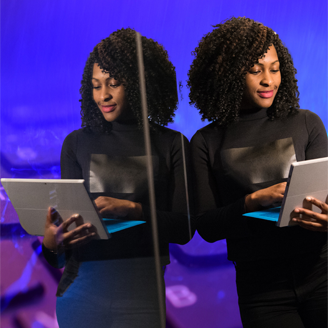 Black woman viewing laptop reflected in mirror