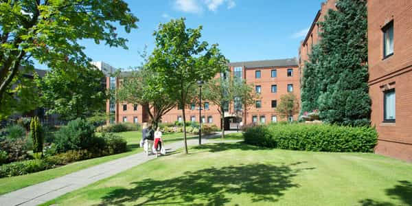 two students walk through the campus village with their shopping bags on a sunny day