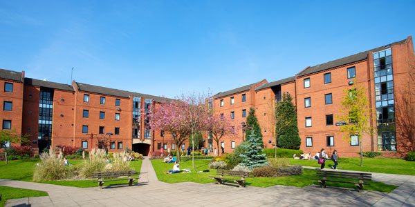 garnett hall in the sunshine with lots of students lounging on the grass outside