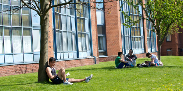 students sitting in the sunshine on the grass outside thomas campbell court