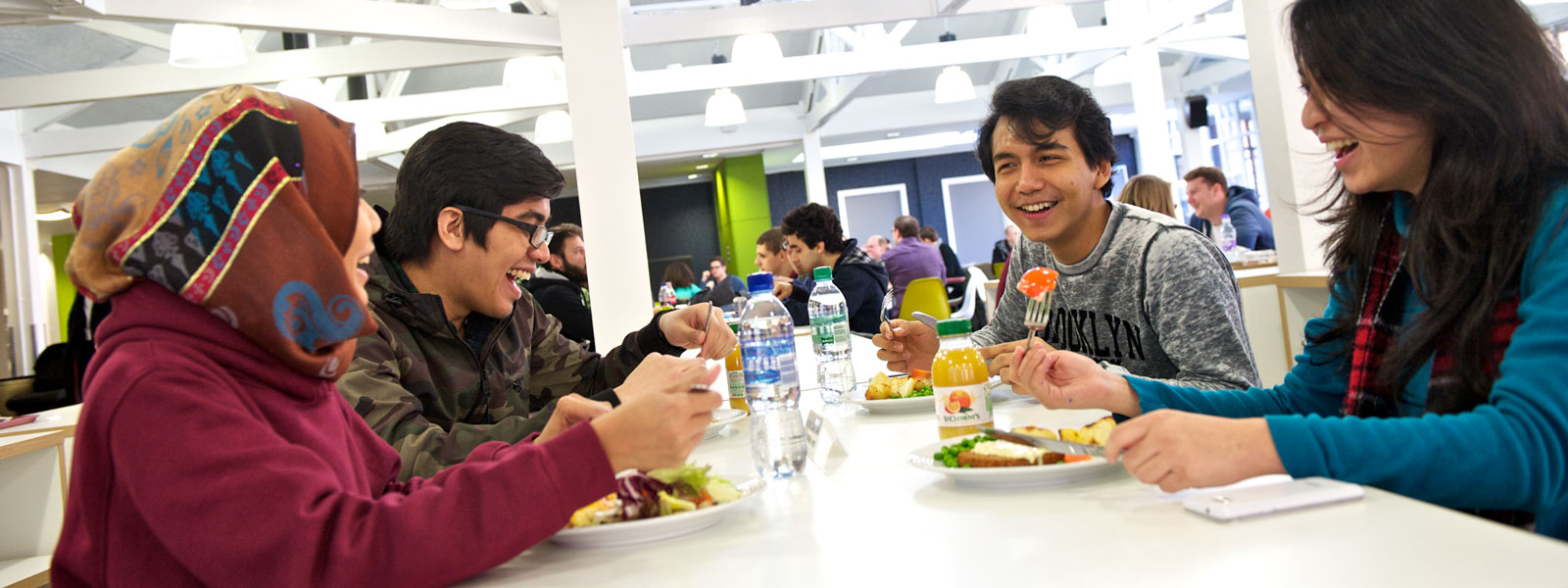 four students laugh while eating together in a Strathclyde cafe