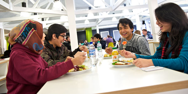 a group of students sit eating and laughing together in the Lord Todd cafe