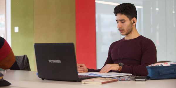a male student uses a laptop in the library