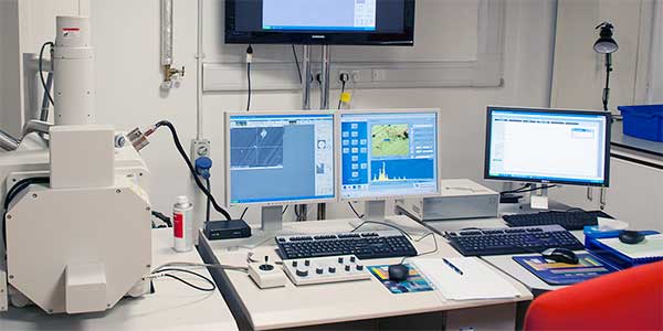 Microscope and computer screens in lab.