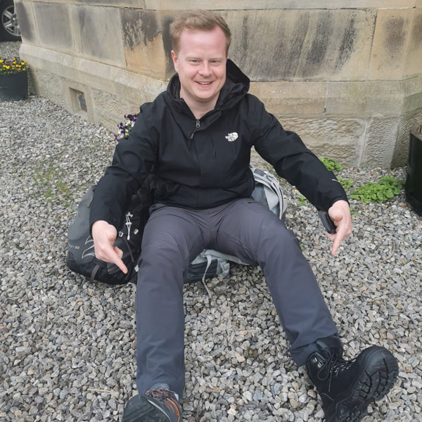 Donald Robertson sitting on gravel, smiling at the camera