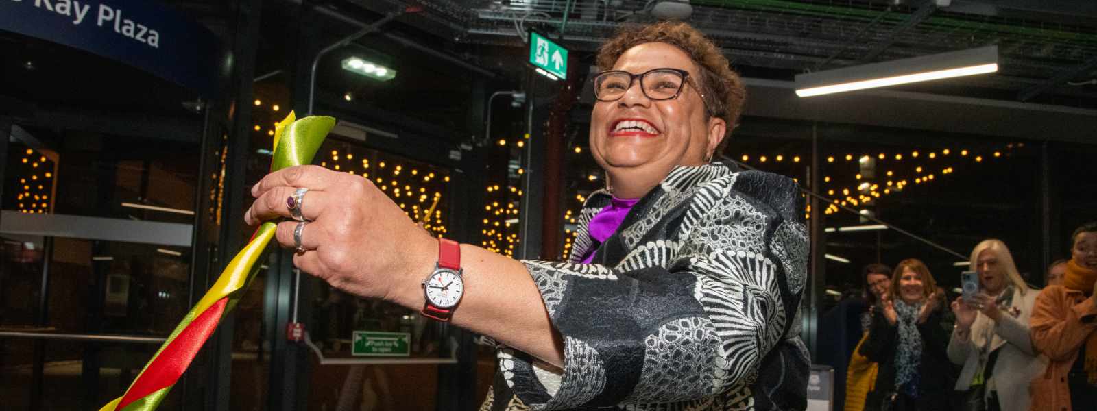 Jackie Kay cuts a ribbon with scissors to officially open the Plaza named in her honour.