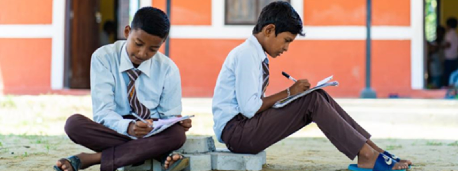 Pupils sit outside the new school studying