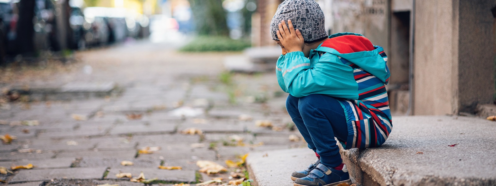 A small boy sitting alone on steps in the street