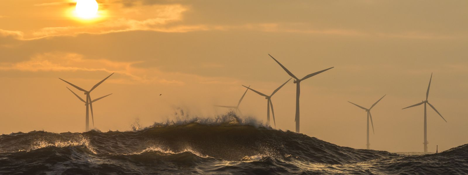 Offshore wind turbines behind large waves.