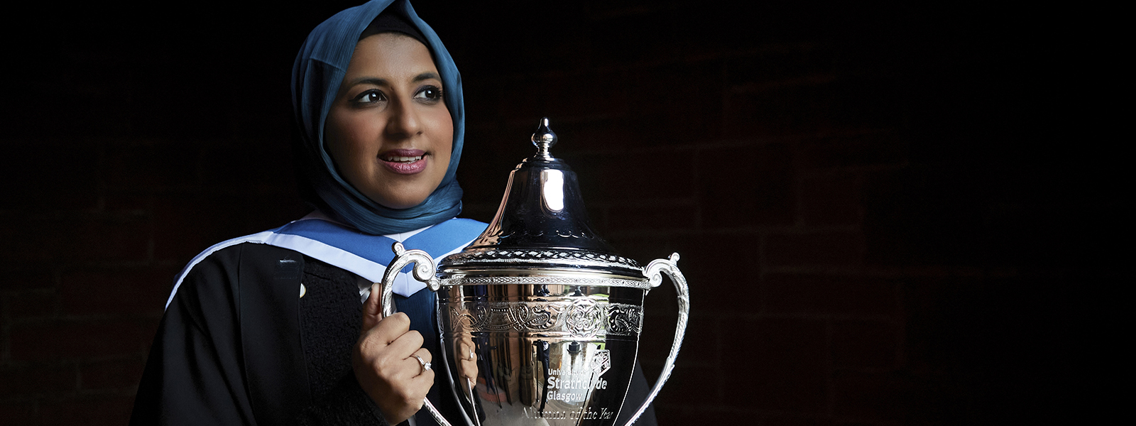 Zara Mohammed holding the silver Alumnus of the Year Trophy