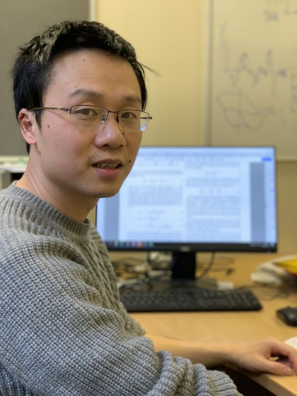 Professor Weijia Yuan sitting at his computer.