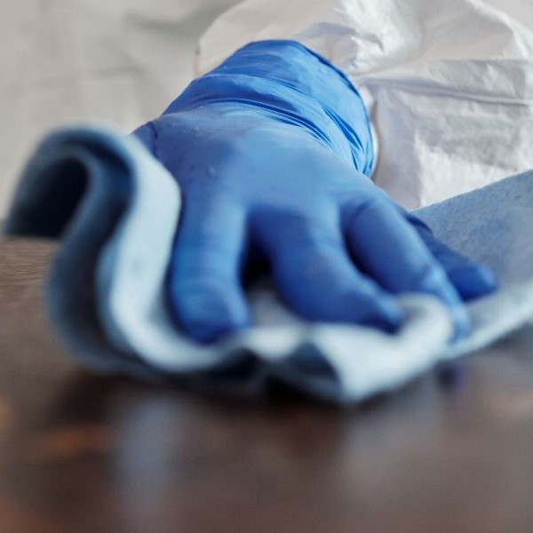 A gloved hand wipes a surface clean