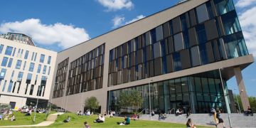 People sit on the grass outside the Technology and Innovation Centre on a sunny day