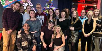 The Conferencing and Events team gathered around a restaurant Christmas tree